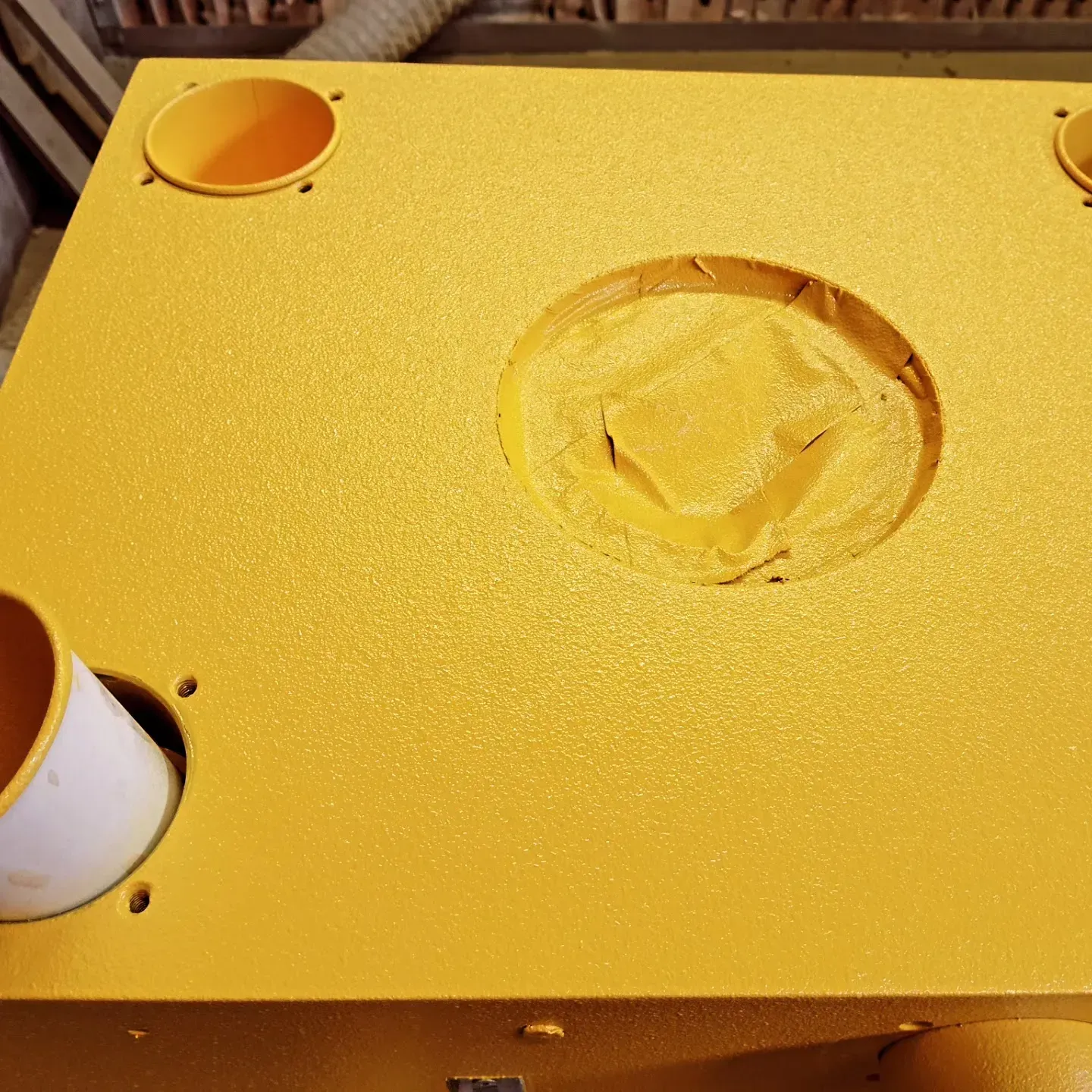 Una mesa amarilla con un agujero en el medio y dos tazas sobre ella.