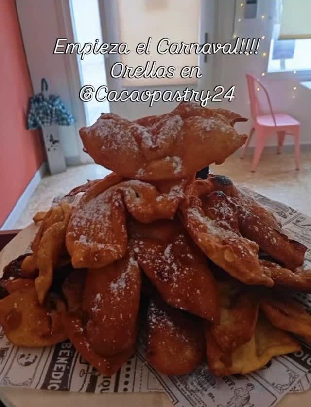 Montón de pasteles fritos dorados espolvoreados con azúcar sobre una mesa, con un texto en español superpuesto al fondo.