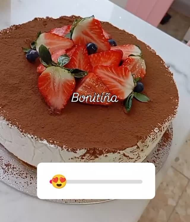 Pastel de chocolate cubierto con fresas y arándanos en un plato blanco.