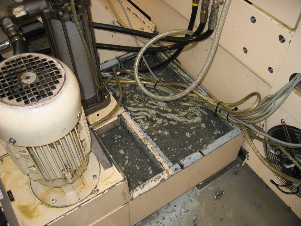Industriemaschinen mit Motor, Kabeln und einer staubigen Metallplattform in einem beengten Geräteraum