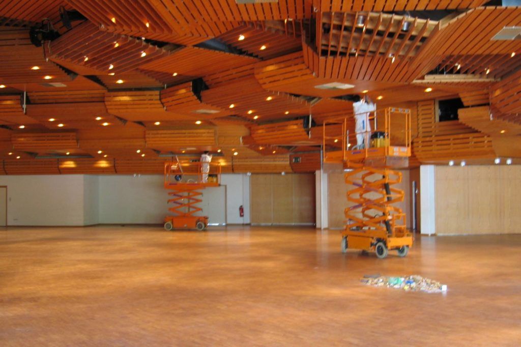 Leere Halle mit Holzdecke, orangefarbenen Aufzügen und poliertem Boden