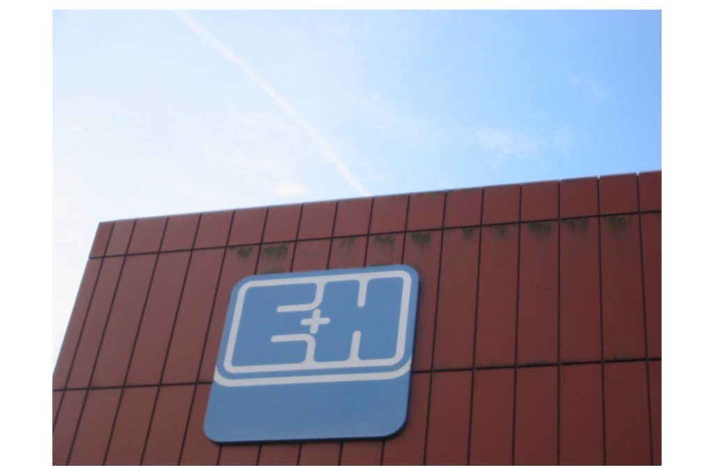 Blaues Schild an einem roten Gebäude vor hellem Himmel
