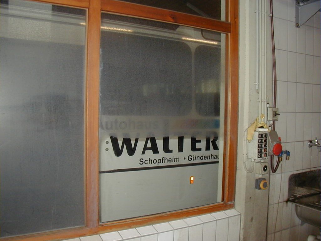 Innenfenster mit Milchglas und einem „WALTER“-Schild neben einer gefliesten Wand und einem Waschbeckenbereich