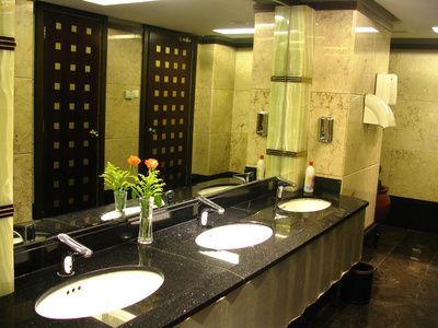 Modernes Badezimmer mit Doppelwaschbecken, schwarzer Arbeitsplatte, großem Spiegel und beigefarbenen Fliesenwänden