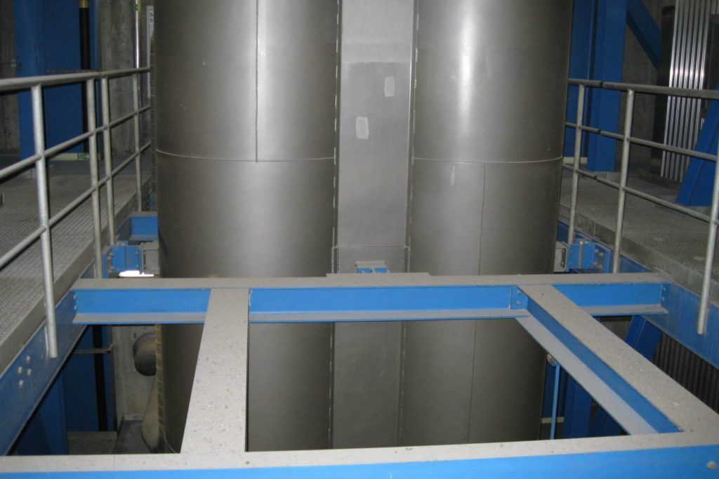 Industrielles Interieur mit großen silbernen Tanks und blauen Metallgeländern über einem offenen Bodenausschnitt