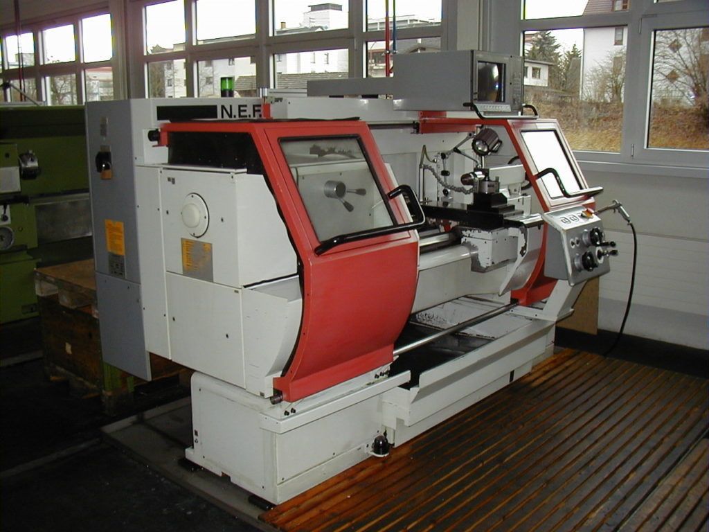 Große rot-weiße Industriemaschine in einer Werkstatt mit Fenstern und Holzboden.