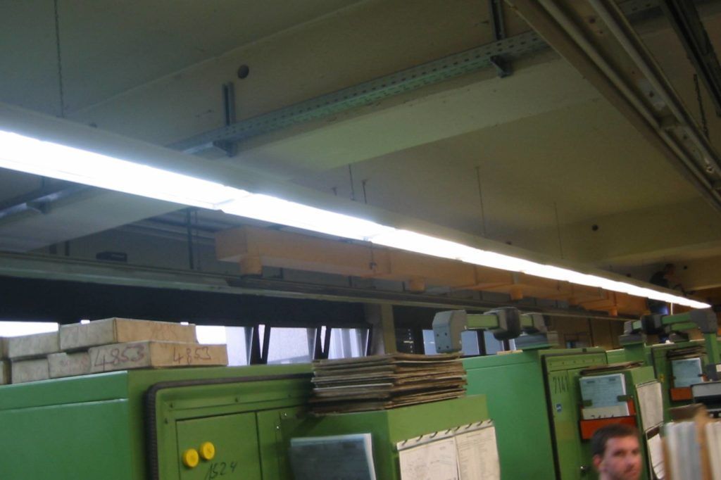 Industrielle Deckenleuchten über grünen Maschinen in einer Werkstatt