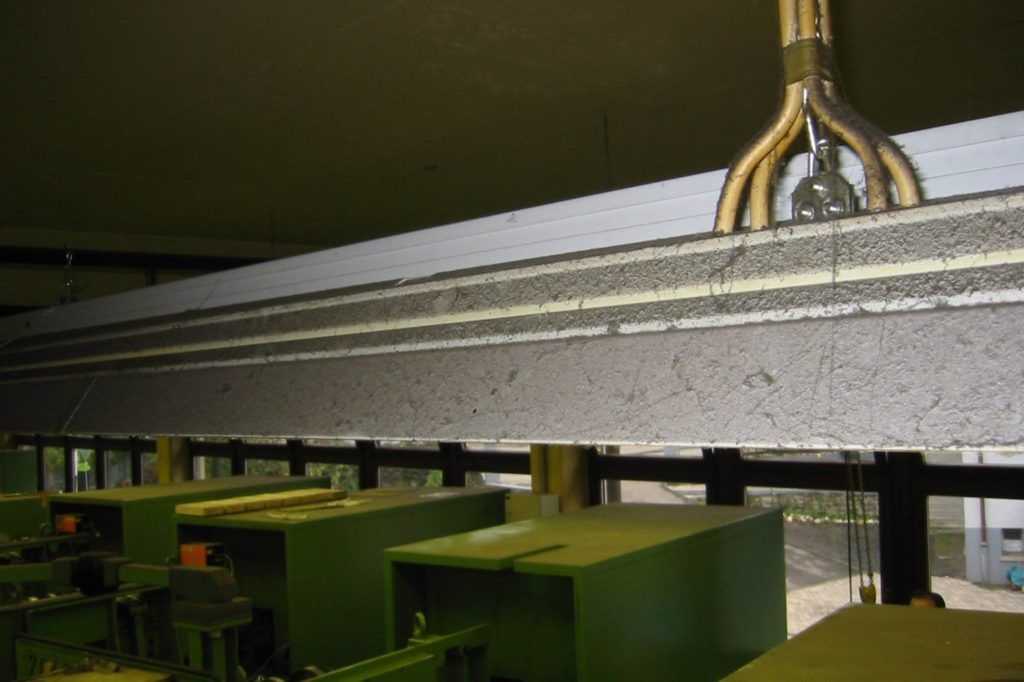 Industrielles Förderband mit grünen Kisten, die sich unter einer Metallmaschine in einer Fabrikumgebung bewegen
