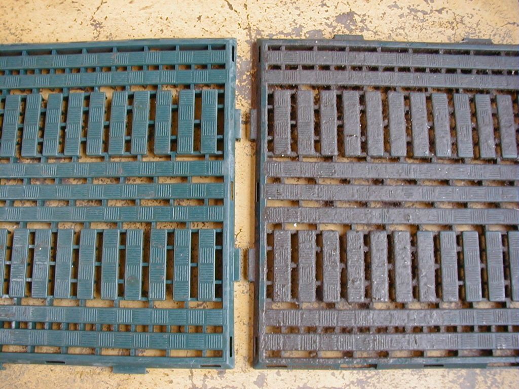 Blaue und braune Metallbodenroste liegen nebeneinander auf einer Betonfläche.