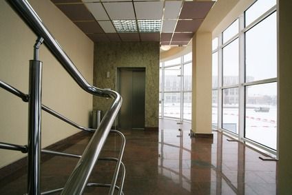 Leerer, moderner Flur mit großen Fenstern, glänzenden Böden und einem Metallgeländer