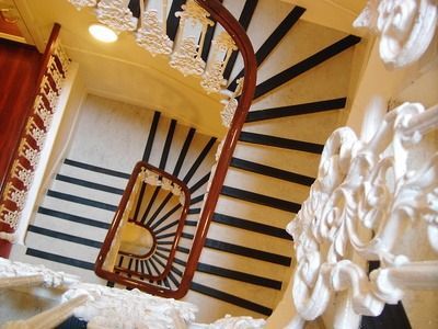 Wendeltreppe mit schwarz-weißen Stufen und verziertem weißen Geländer im Inneren eines Gebäudes