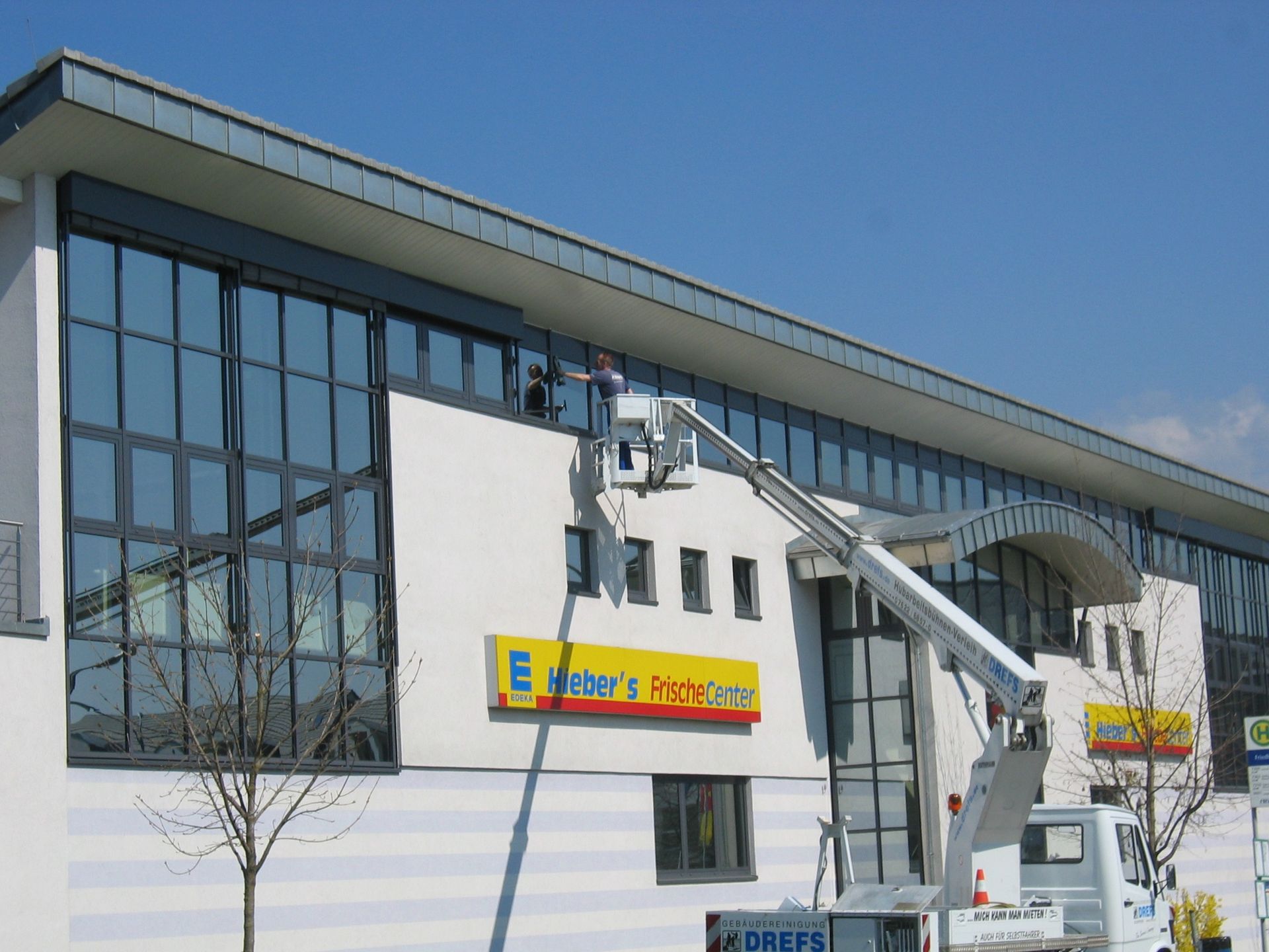 Modernes weißes Gebäude mit großen Glasfenstern und einem Ladenschild unter blauem Himmel