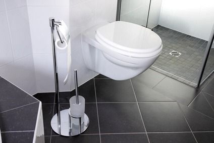Modernes, weißes Wand-WC mit Chrom-Bidet in einem gefliesten Badezimmer