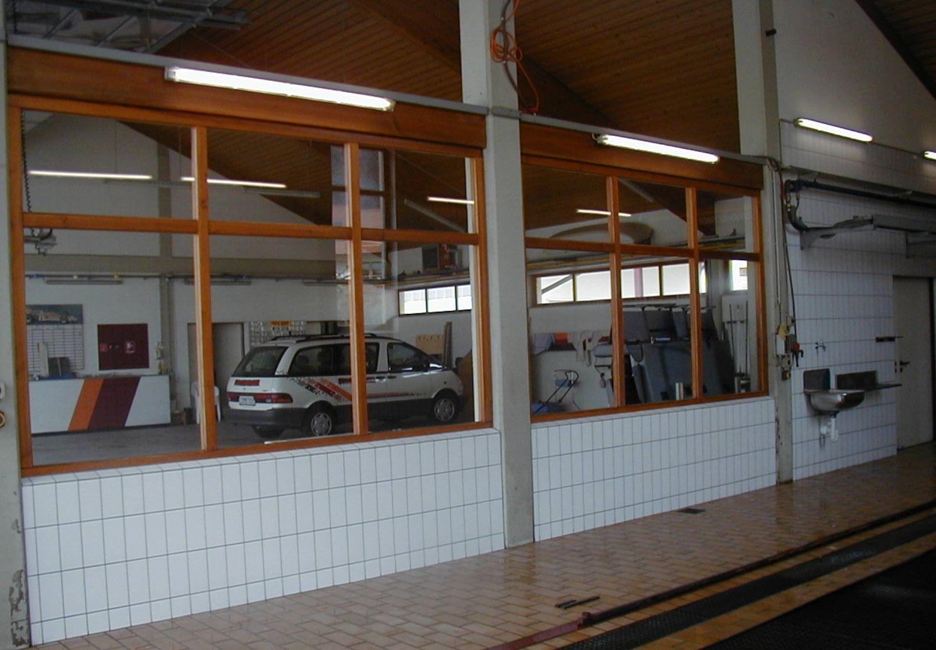 Autowerkstatt mit orangefarben umrandeten Fensterscheiben und mehreren Autos im Inneren