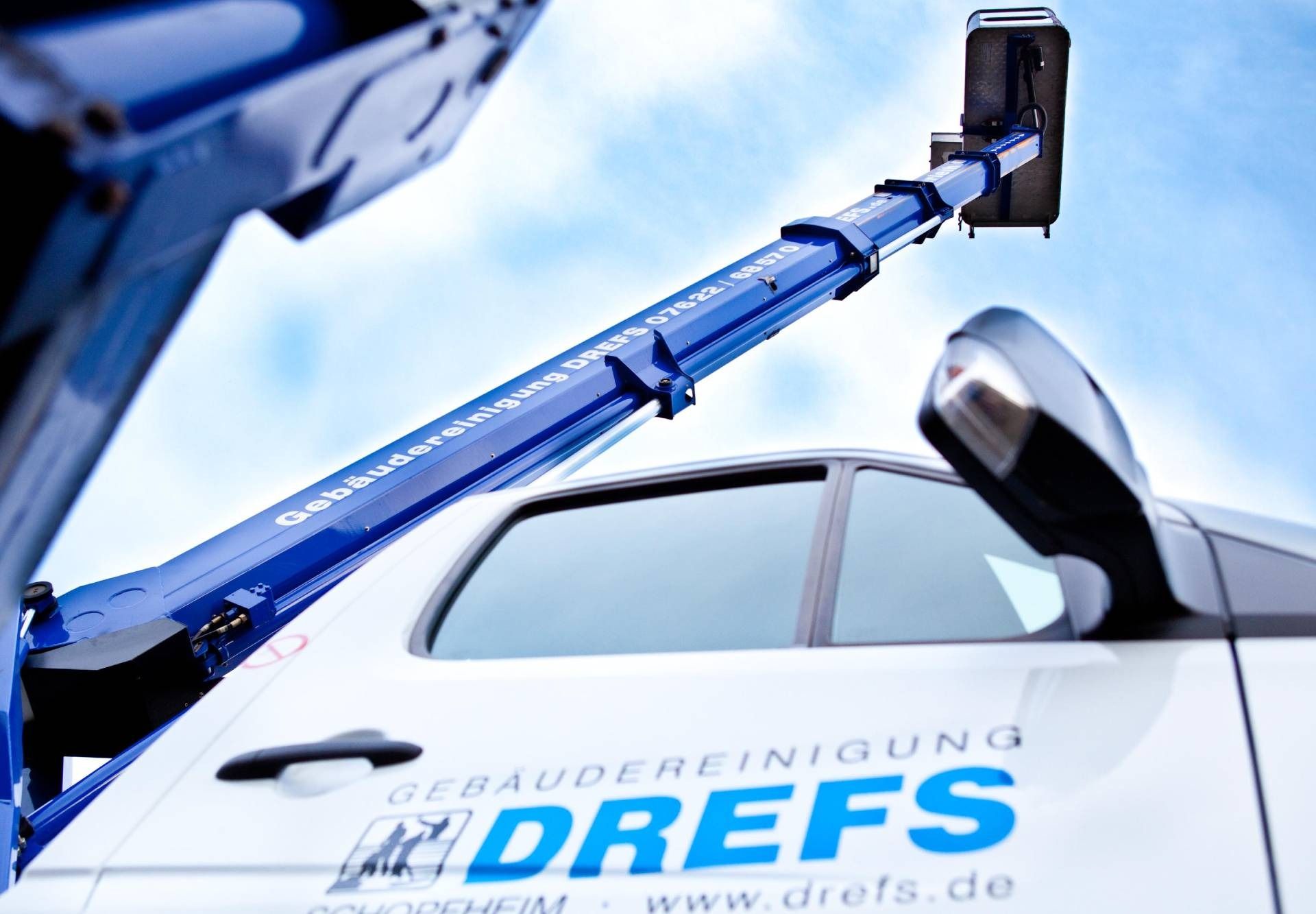 Ein blauer Abschleppwagen hebt einen weißen DREFS-Pkw am Vorderrad an.