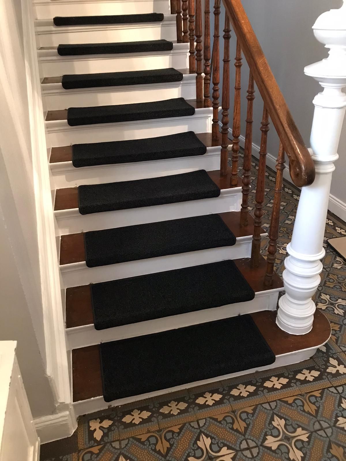 Eine Treppe mit schwarzem Teppich auf den Stufen und einem Holzgeländer.
