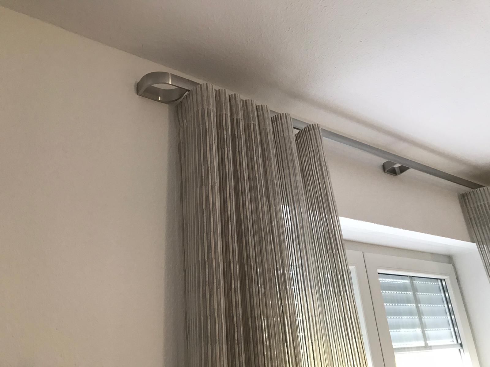 Neben einem Fenster hängen zwei Vorhänge von der Decke.