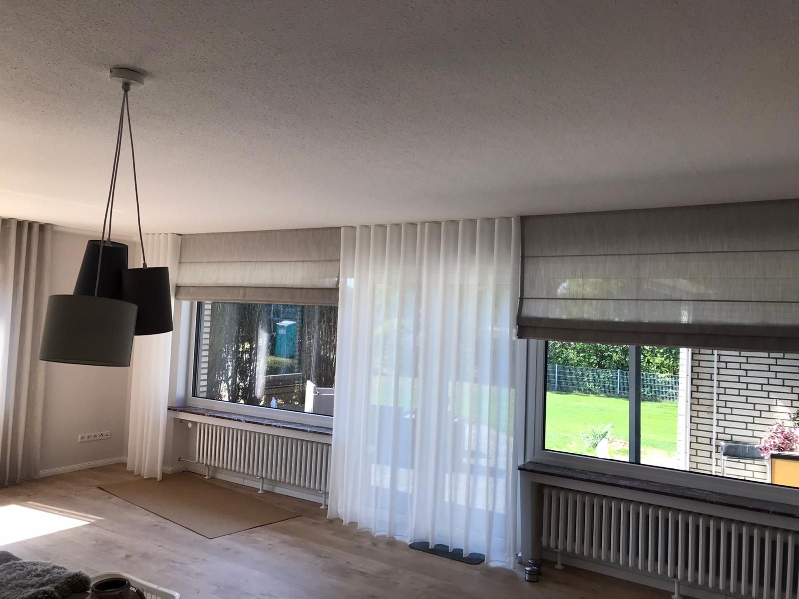 Ein Wohnzimmer mit vielen Fenstern und Vorhängen.