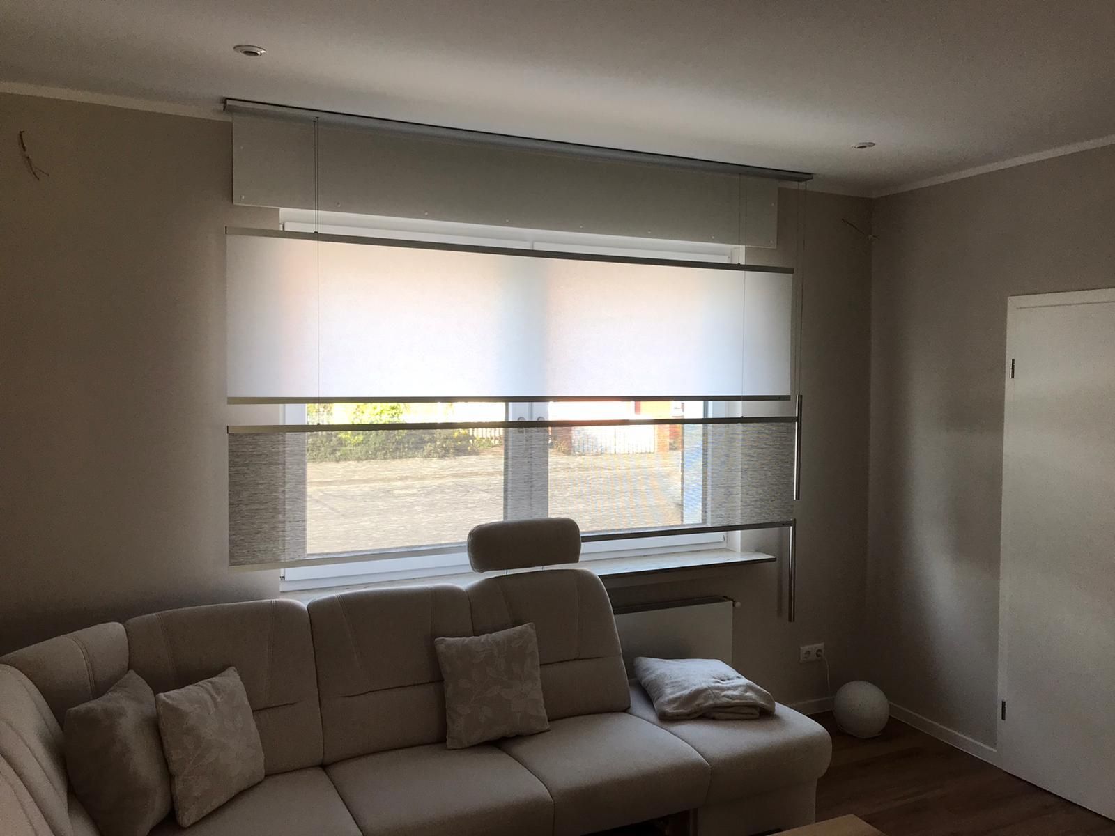 Ein Wohnzimmer mit einer Couch und einem Fenster mit Jalousien.