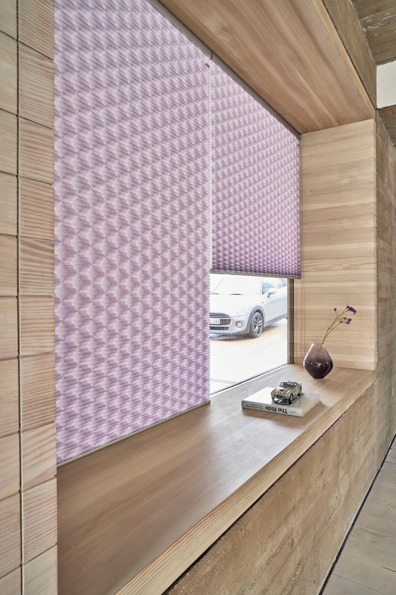 Ein Fenster mit violetten Jalousien und einer Vase auf der Fensterbank.