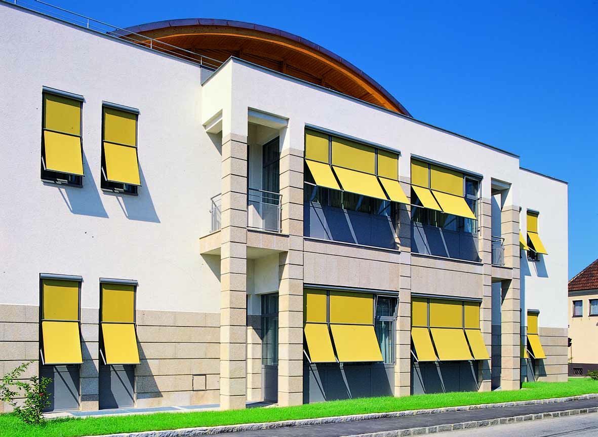 Ein weißes Gebäude mit gelben Markisen an den Fenstern