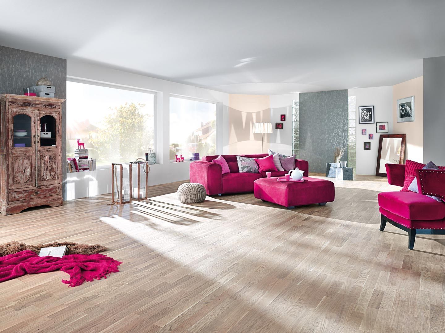 Ein Wohnzimmer mit einer rosa Couch, einem Sessel und einem Ottomanen.