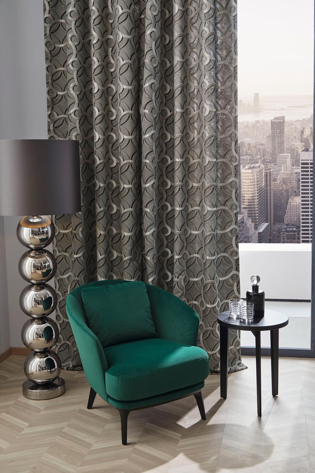 In einem Wohnzimmer steht ein grüner Stuhl neben einer Lampe und einem Tisch.