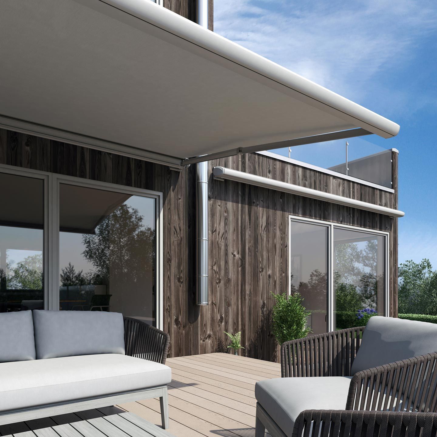 Eine Terrasse mit Sofa und Sessel unter einer Markise