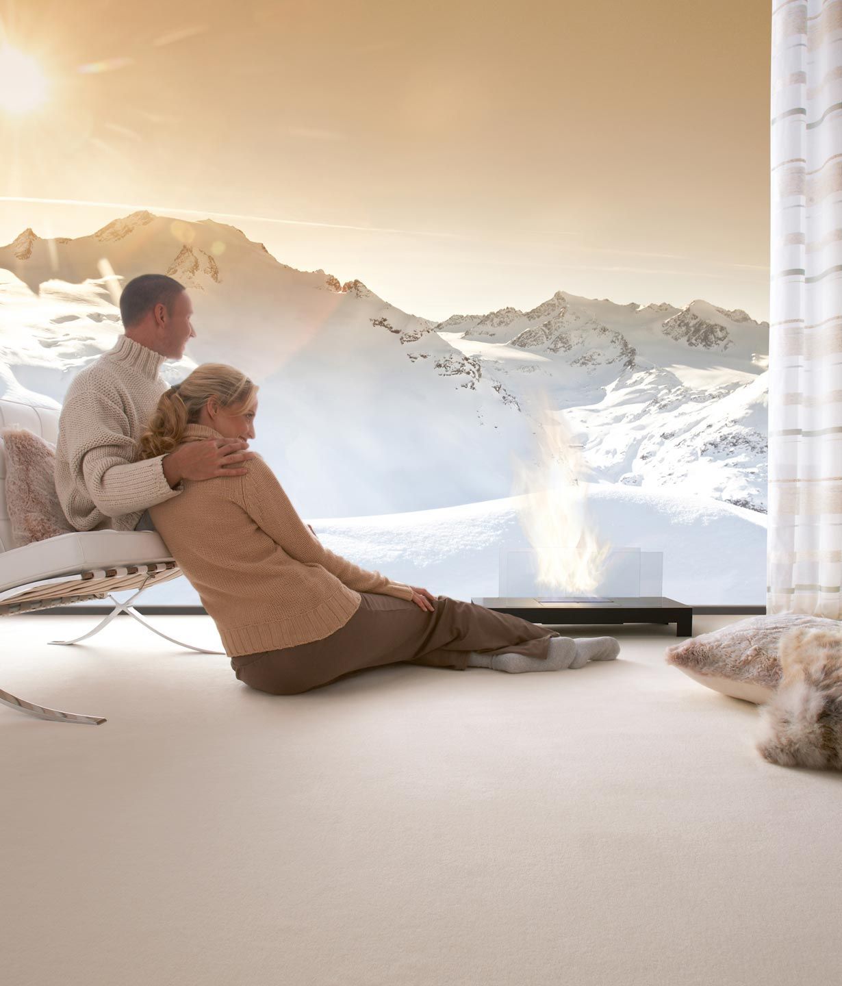 Ein Mann und eine Frau sitzen auf dem Boden vor einem Fenster mit Bergen im Hintergrund.