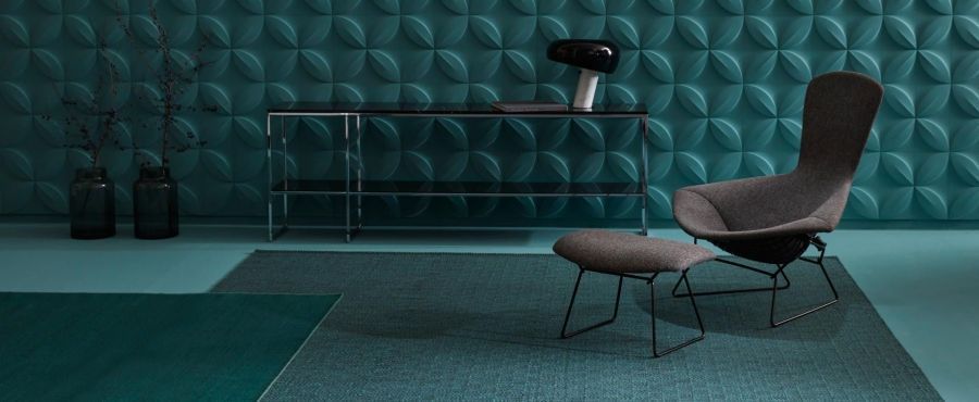 Ein Sessel und ein Ottomane stehen auf einem Teppich in einem Wohnzimmer.