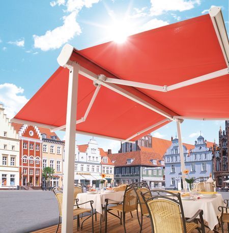 Ein Restaurant mit Tischen und Stühlen unter einer roten Markise