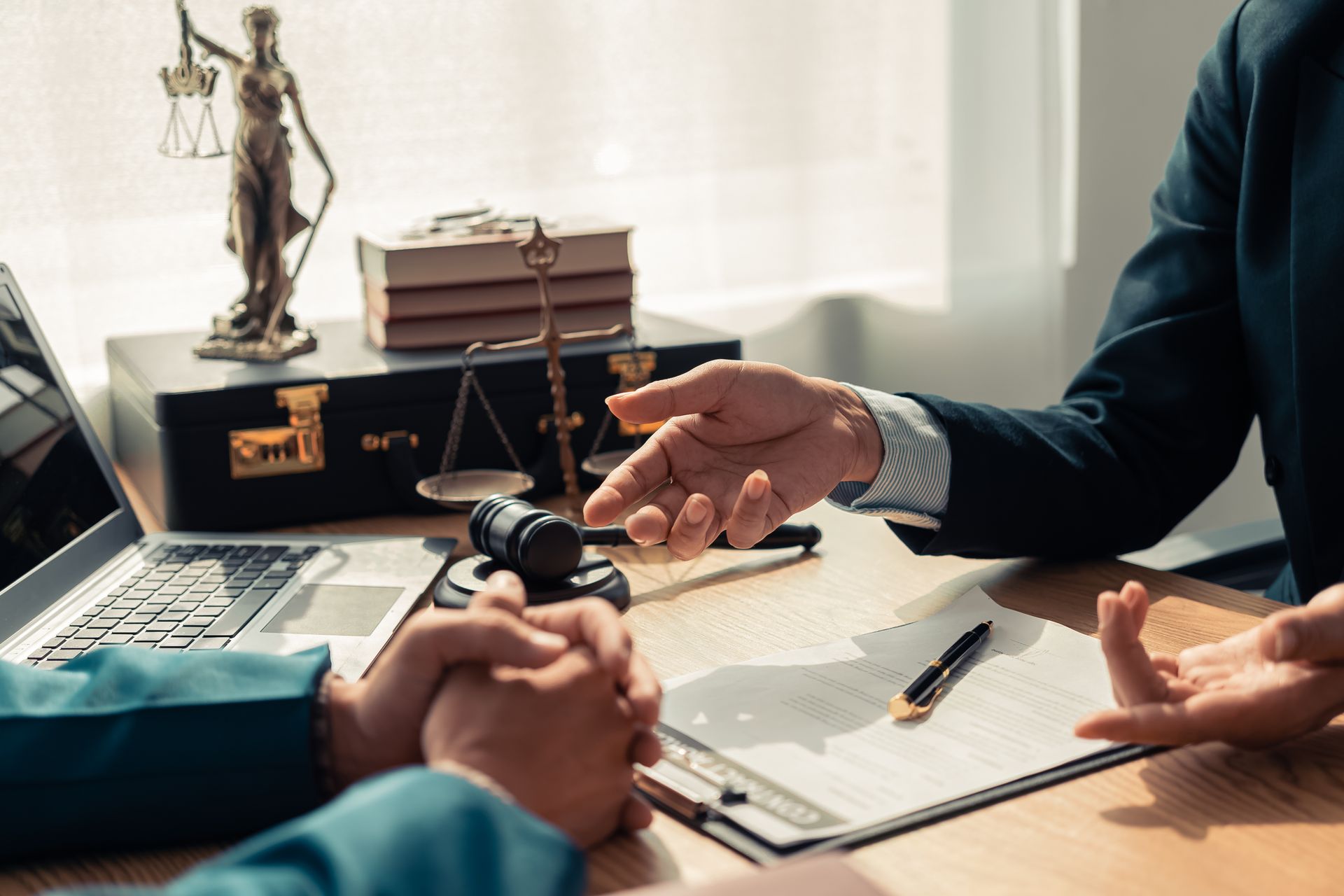 Deux personnes assises à un bureau examinent des documents. Gestes d'avocat, balance de la justice et marteau de juge visibles.