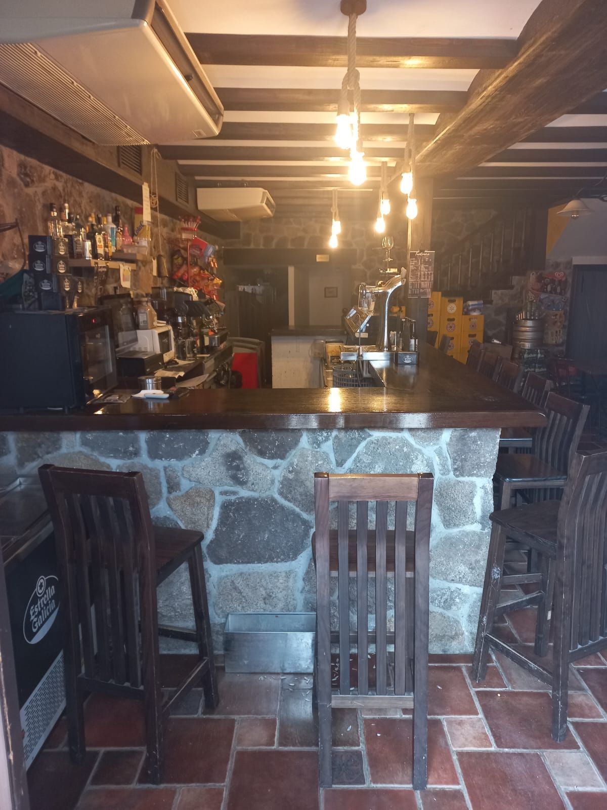 Un bar con encimera de piedra y sillas de madera.