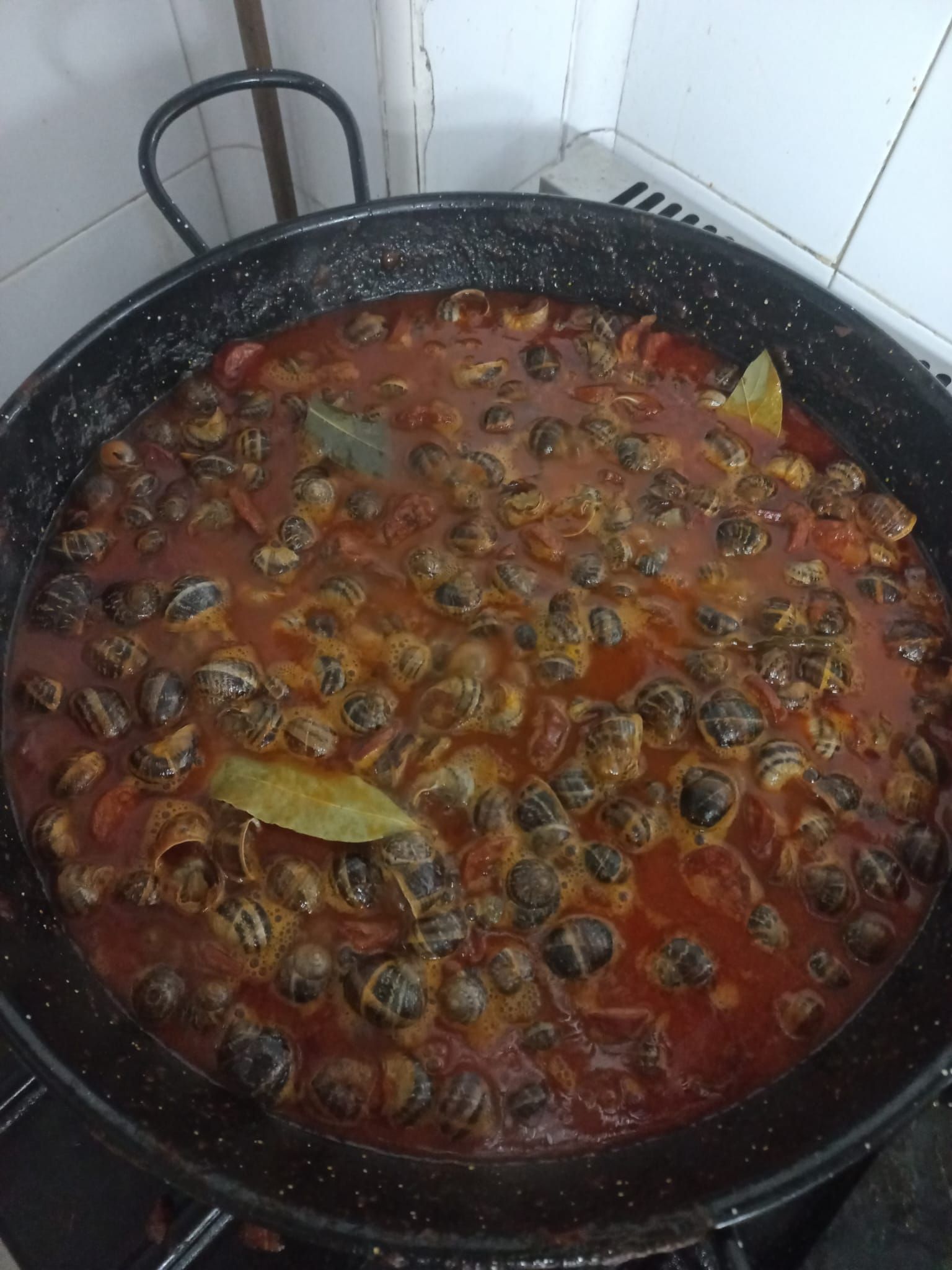 Una sartén llena de caracoles y salsa de tomate en una estufa.
