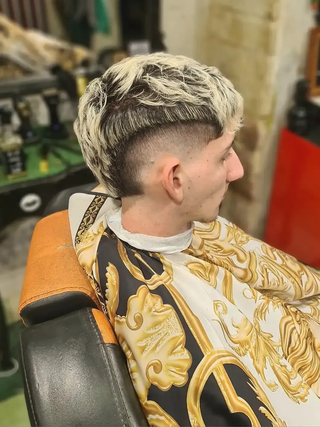 Silla de barbero con un cliente mostrando un corte de pelo degradado recién hecho.
