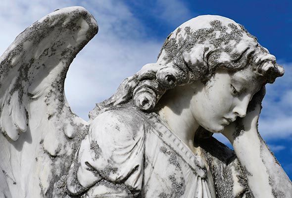 Una estatua de un ángel con la mano en la cara.