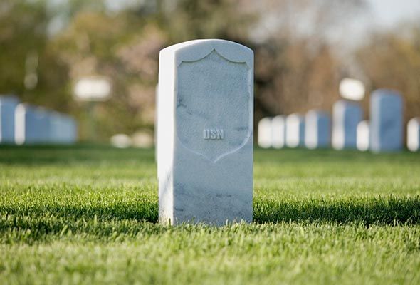 Una lápida blanca se encuentra en medio de un campo de hierba.