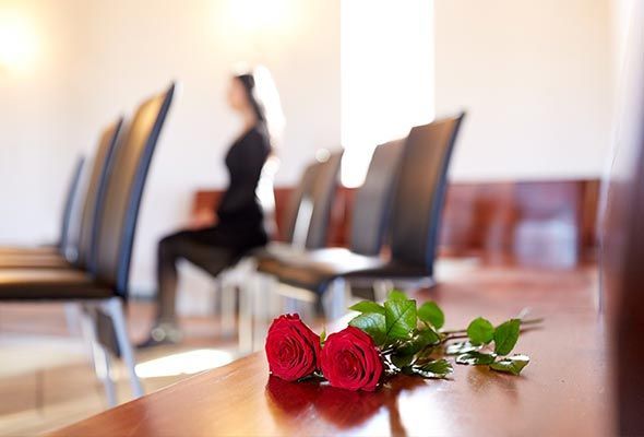 Dos rosas rojas están sobre una mesa en una funeraria.