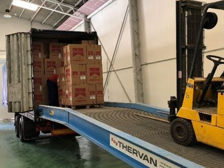 Una carretilla elevadora está cargando cajas en un camión en un almacén.