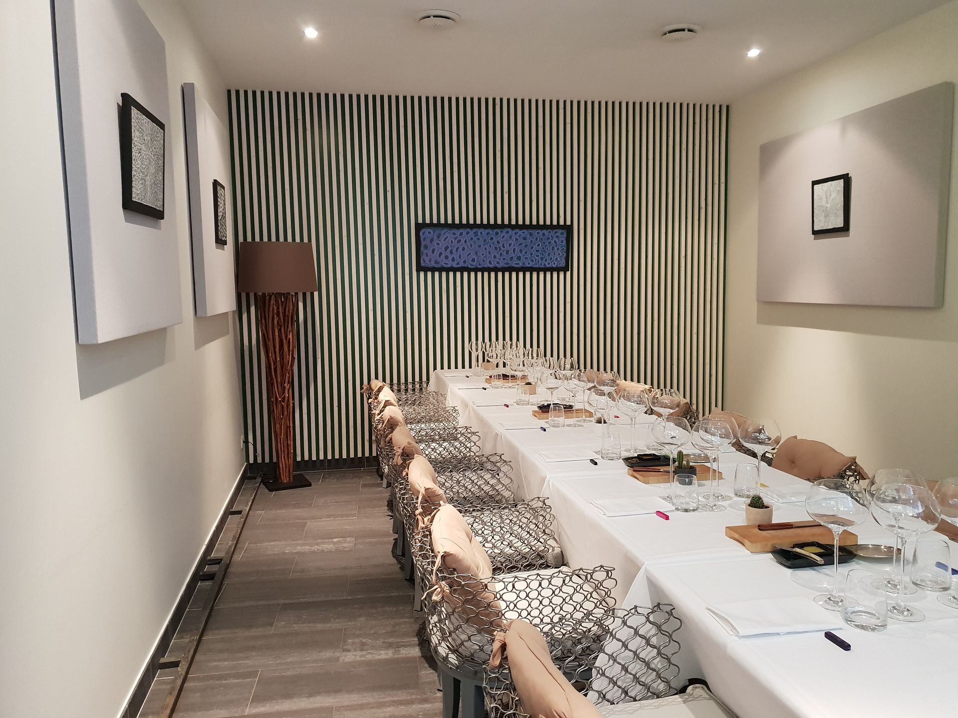 Une longue table à manger dans une pièce privée ornée de tableaux. 