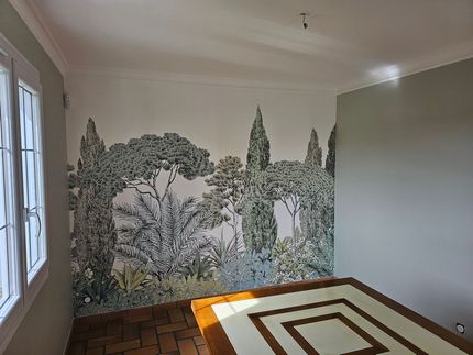 Fauteuil rose et table d'appoint verte sur un papier peint Art déco vert foncé.