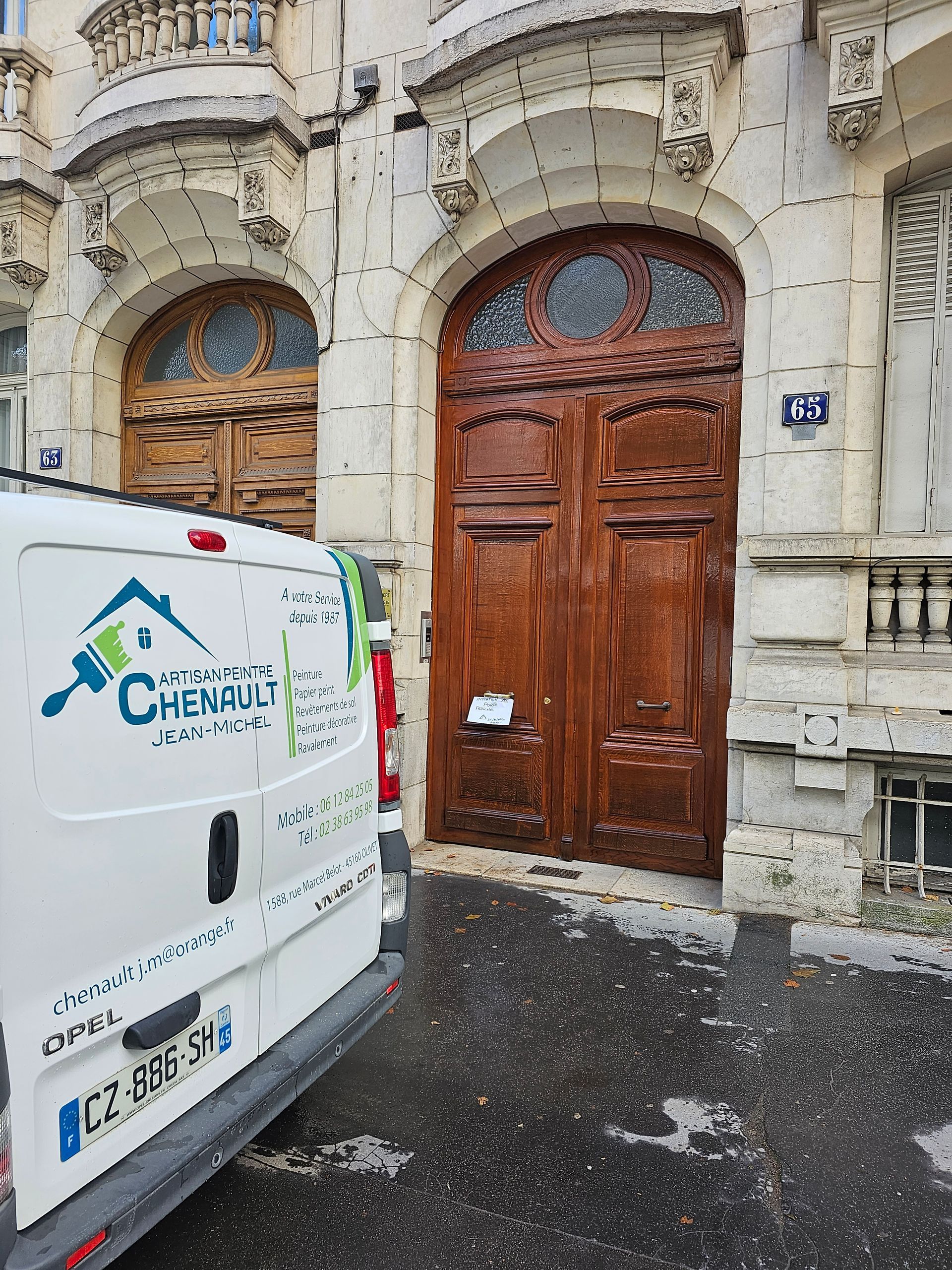 Une camionnette de Chenault Peinture est garée devant un bâtiment doté d'une grande porte en bois brun.