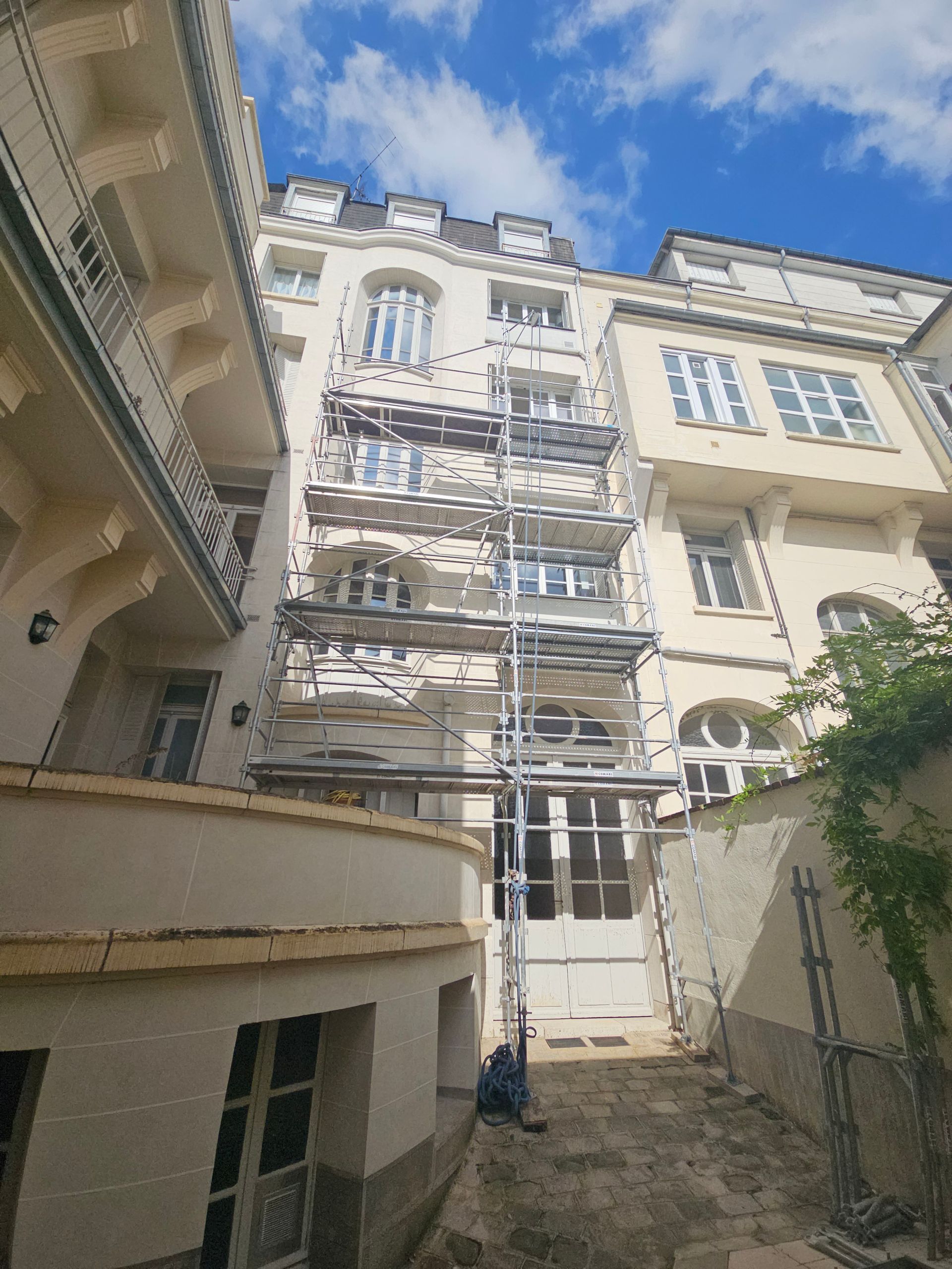 Extérieur d'un bâtiment avec des échafaudages pour des réparations ; ciel bleu en arrière-plan.