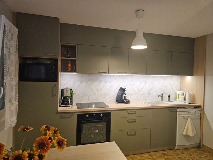 Cuisine moderne avec comptoirs blancs et accents de bois, agrémentée d'un arrangement floral.