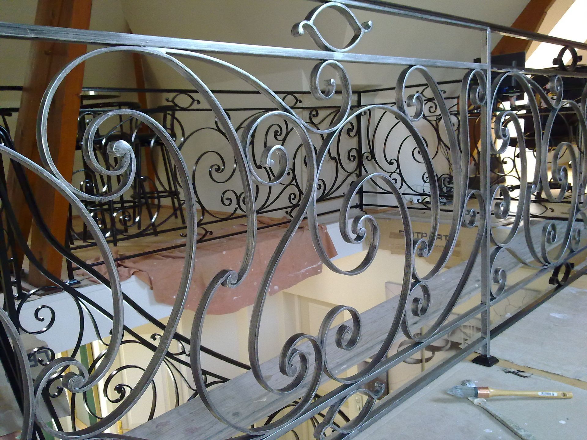 Rambarde en fer forgé ornée sur un balcon, avec des motifs en volutes.