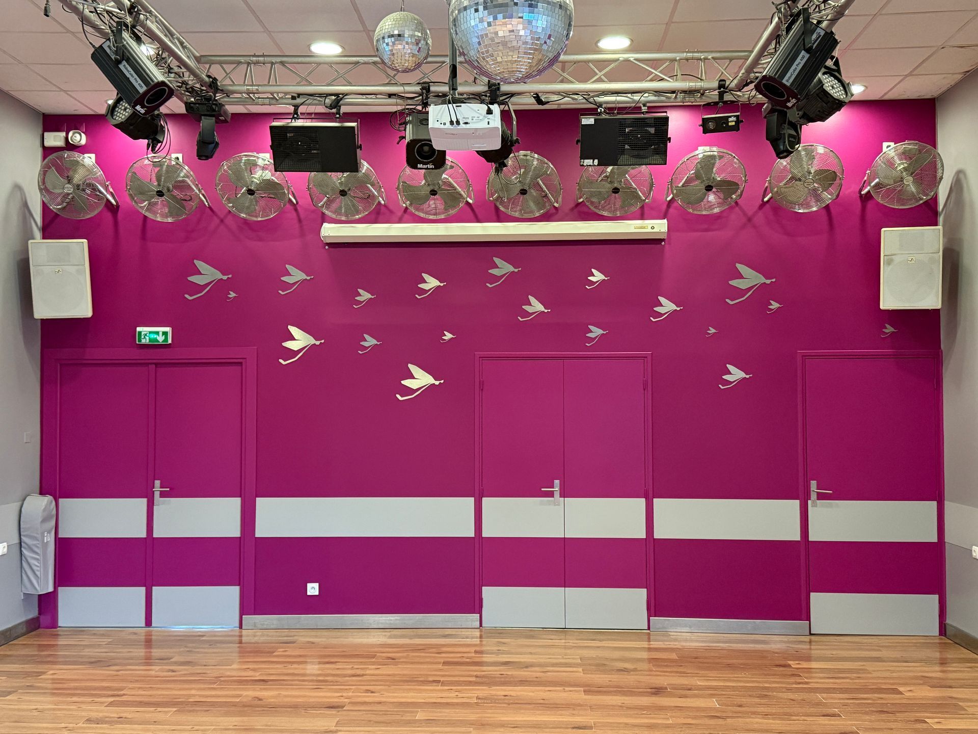 Pièce avec mur bleu, poutres en bois, lustre, armoire, échelle et table.