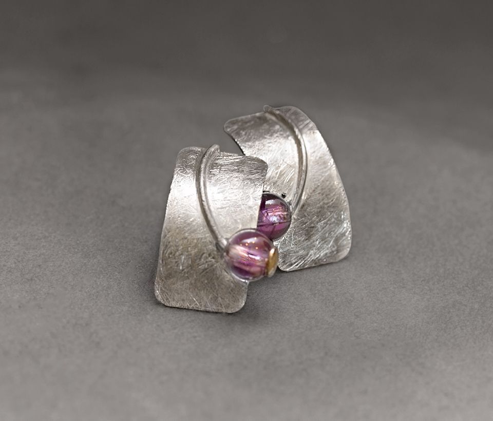 Silberne Ohrringe mit zwei strukturierten, gebogenen Platten, die jeweils ein Paar violette und goldene Perlen halten.