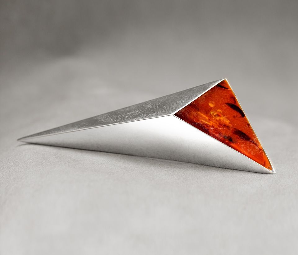 Silberne dreieckige Brosche mit einem Einsatz aus orangefarbenem Bernstein.