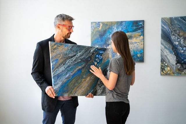 Un hombre y una mujer están parados uno al lado del otro sosteniendo una pintura.