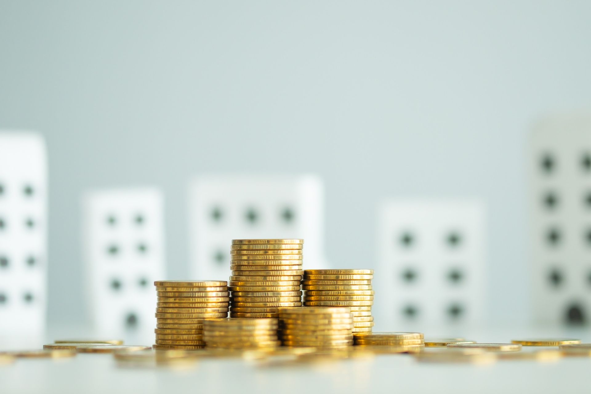Una pila de monedas de oro sobre una mesa con dominós en el fondo.